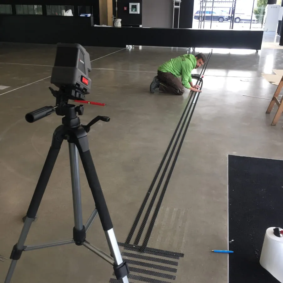 Ein Arbeiter vermisst den Boden mit einem Lasergerät.