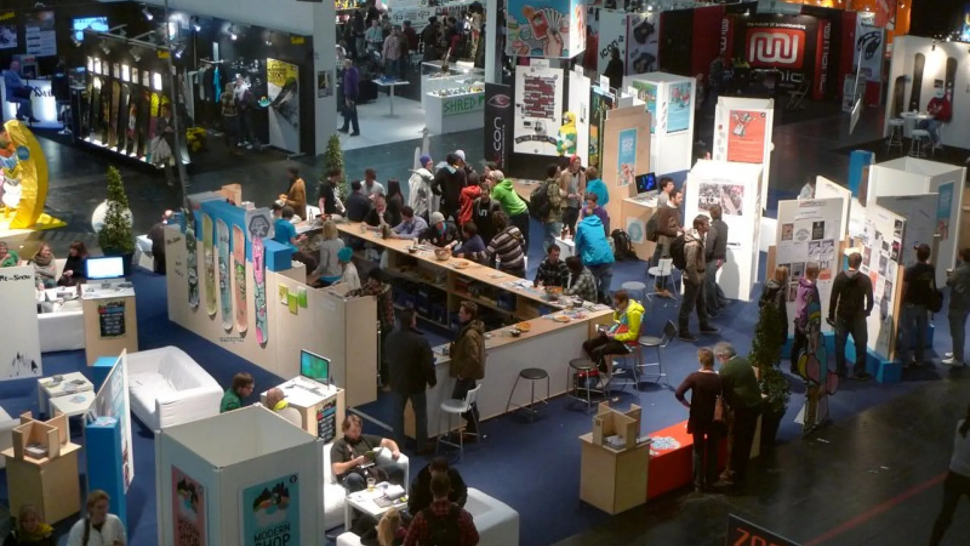 Überblick über eine Messe mit vielen Ständen und Besuchern.