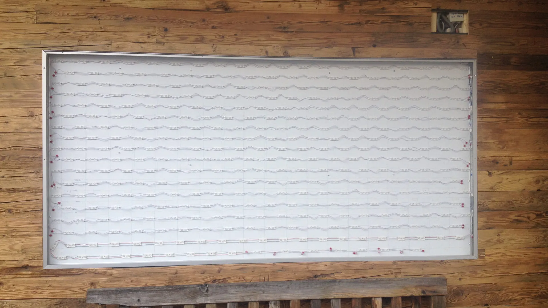 Grafik mit Wellenlinien an einer Holzwand
